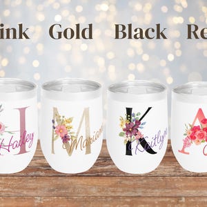 May include: Four stainless steel wine tumblers with floral designs and personalized names. The tumblers are in pink, gold, black, and red.