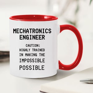 May include: White ceramic mug with a red rim and handle. The mug has black text that reads "Mechatronics Engineer. Caution: Highly trained in making the impossible possible."