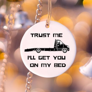 May include: White ceramic ornament featuring a black silhouette of a tow truck and the text "Trust me I'll get you on my bed".