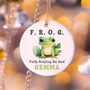 May include: White ceramic ornament with a green frog illustration and the text "F.R.O.G. Fully Relying On God GEMMA".