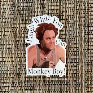 May include: A white sticker with a cartoon image of a man with brown hair and a white tank top. The text on the sticker reads "Laugh While You Can Monkey Boy!"