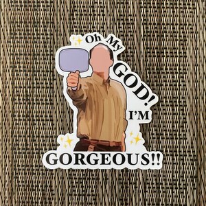 May include: A sticker featuring a cartoon character holding a mirror and saying "Oh My God! I'm Gorgeous!" The sticker has a white background with black text and yellow stars.