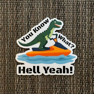 May include: A sticker featuring a green dinosaur riding an orange jet ski on blue water. Text on the sticker reads "You Know What? Hell Yeah!" in black and white. The sticker has a white border.