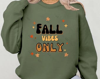 Może przedstawiać: Zielony sweter z napisem "Fall Vibes Only" w retro czcionce. Tekst jest otoczony małymi grafikami liści i gwiazd.