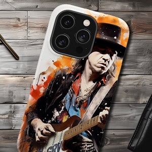 May include: A white phone case with a colorful watercolor design featuring a musician playing a guitar. The musician is wearing a black hat and a black leather jacket. The phone case has a cutout for the camera lens.