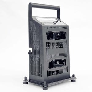 May include: A black, rectangular 3D scanner with a handle on top. The scanner has a clear plastic cover over the lens and a black base with four rubber feet.