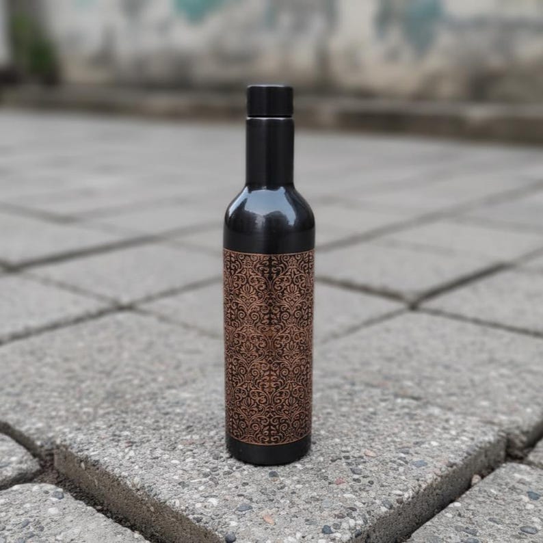 Handmade pure copper water bottle with polished finish and engraved detailing, Ayurvedic wellness drinkware ideal for yoga lifestyle and eco friendly reusable hydration.