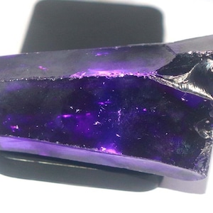 Könnte beinhalten: Ein großer, facettierter, violetter Edelstein mit einer rauen, natürlichen Oberfläche. Der Edelstein ist durchscheinend und hat eine tiefe, satte violette Farbe.