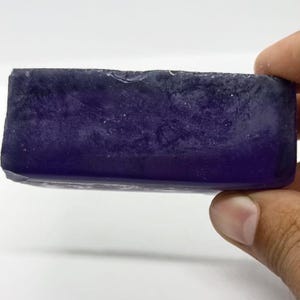 Könnte beinhalten: Ein großes, rechteckiges Stück violetter Amethystkristall. Der Kristall ist durchscheinend und hat eine glatte, polierte Oberfläche.