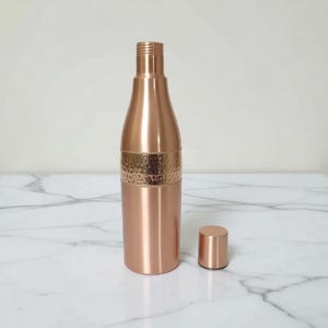 Solid copper drinking bottle with leak proof lid, traditional Indian Ayurvedic vessel for storing water overnight for health benefits.