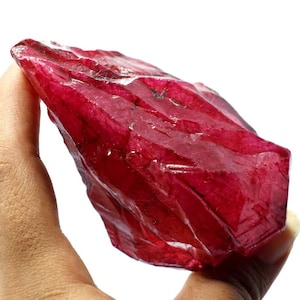 Puede incluir: Un gran cristal de rubí facetado de color rojo intenso. El cristal es áspero y tiene un aspecto natural sin pulir.