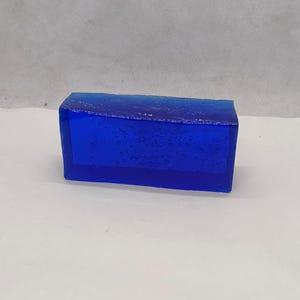 以下が含まれることがあります： 表面がテクスチャ加工された、濃い青色の長方形の石鹸のブロックです。