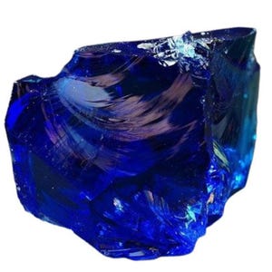 Puede incluir: Un gran cristal azul en bruto con vetas iridiscentes. El cristal tiene un color azul intenso y una apariencia ligeramente nublada.
