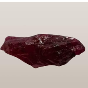 Peut inclure: Une pierre précieuse brute de couleur rouge foncé avec une forme irrégulière naturelle.