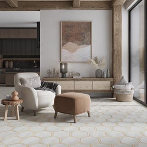 May include: A living room with a white armchair, a brown ottoman, and a wooden coffee table. The room has a white wall with a painting on it, a wooden floor, and a large window.