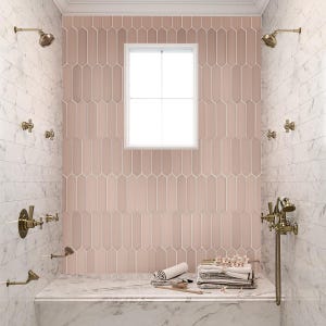 May include: A pink tiled shower with a window and a marble bench. The shower has multiple shower heads and gold fixtures. There are towels and a brush on the bench.