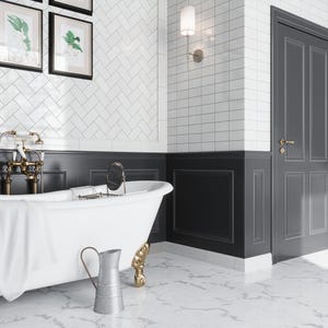 May include: A white clawfoot bathtub with a white towel on the side, a gold faucet, and a silver pitcher on the floor. The bathroom has white subway tiles with a black wainscoting and a black door.