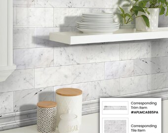 May include: White marble subway tile backsplash with a white shelf above it. There are three white ceramic canisters on the counter below the backsplash. The canisters have wooden lids and one has the word "sugar" printed on it. There are two small images below the backsplash showing the corresponding trim and tile items with their product numbers: #APLMCAB85PA and #APLFCAB836PA.