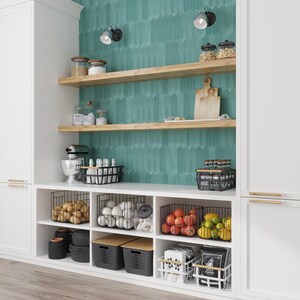 May include: White kitchen cabinets with open shelves and wire baskets filled with produce, jars, and kitchen tools. The backsplash is teal green tile with a geometric pattern.