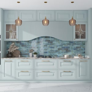 May include: A kitchen with light blue cabinets and a blue and green tiled backsplash. Three gold pendant lights hang over the counter. The counter has a light brown countertop and gold cabinet pulls.