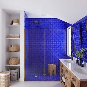 May include: A bathroom with a walk-in shower featuring blue patterned tiles. The shower has a glass door and a brass shower head. The bathroom also has a double vanity with a marble countertop and wooden cabinets.