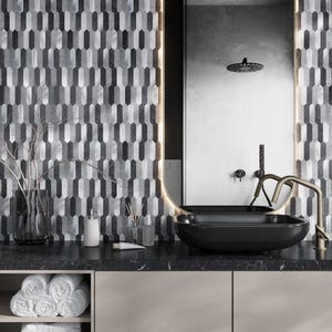 May include: A modern bathroom vanity with a black countertop and a black vessel sink. The sink has a gold faucet and is set against a backdrop of gray and black geometric tiles.