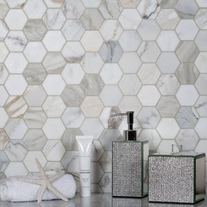 May include: White hexagonal marble tiles with a white towel, a white tube of hair care product labeled "Hydrating Conditioner", and two silver containers with a sparkly finish.