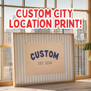 Puede incluir: Una impresión enmarcada con un fondo a rayas azul y blanco y un inserto beige con el texto "CUSTOM EST. 1234" en azul. La impresión está sobre una superficie de madera frente a una ventana con vista a la ciudad.