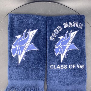 May include: Two navy blue hand towels with white embroidered logos and text. One towel features the text "YOUR NAME" and "CLASS OF '05". The towels have a fringed edge and a Viking logo.