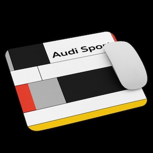 May include: A rectangular mousepad with a geometric design in black, white, red, gray, and yellow, with the text "Audi Sport" in black. A white wireless mouse is on the right side of the mousepad. The background is black.