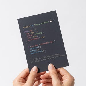 K&ouml;nnte beinhalten: Eine rechteckige schwarze Gru&szlig;karte mit farbigem Programmiercode-Text, der lautet: console.log("Happy Birthday! 🎂"); const you = { age: age + 1, status: "amazing", cake: true, deservesBest: true }; if (you.age > yesterday.age) { celebrate(); eatCake(); openPresents(); } // TODO: have the best day ever // no bugs today, only birthday vibes