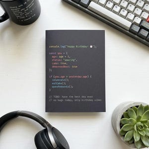 K&ouml;nnte beinhalten: Eine schwarze rechteckige Gru&szlig;karte mit farbigem Programmiercode-Text: console.log("Happy Birthday! 🎂"); const you = { age: age + 1, status: "amazing", cake: true, deservesBest: true }; if (you.age > yesterday.age) { celebrate(); eatCake(); openPresents(); } // TODO: have the best day ever // no bugs today, only birthday vibes