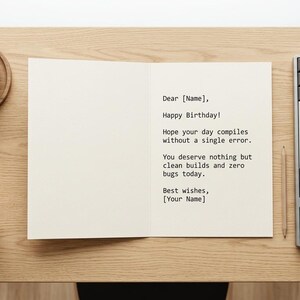K&ouml;nnte beinhalten: Eine offene Gru&szlig;karte mit schwarzem Text: Dear [Name], Happy Birthday! Hope your day compiles without a single error. You deserve nothing but clean builds and zero bugs today. Best wishes, [Your Name]. Daneben befindet sich eine mechanische Tastatur.