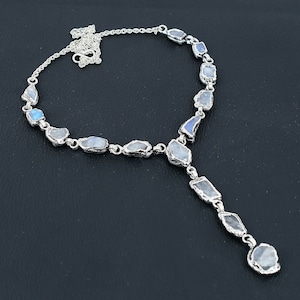 May include: A silver necklace with a long pendant featuring multiple iridescent moonstone stones set in silver.