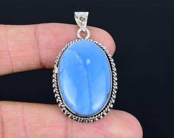 May include: Oval-shaped pendant with a light blue gemstone. The stone is set in a silver-colored metal frame with a twisted rope design around the edge. The pendant has a small loop at the top for a chain.