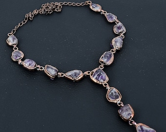 May include: A copper wire necklace with a Y-shaped design features a row of amethyst stones along the top and a single amethyst stone dangling from the bottom.