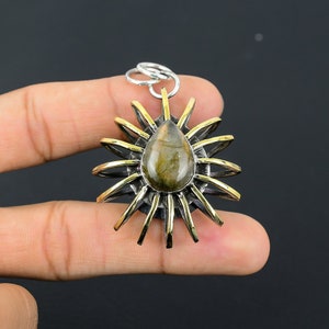 May include: A silver and gold pendant with a teardrop-shaped labradorite gemstone set in a sunburst design.