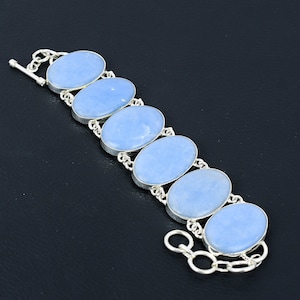Könnte beinhalten: Ein silbernes Armband mit sechs ovalen blauen Edelsteinen. Das Armband hat einen Schiebeverschluss.