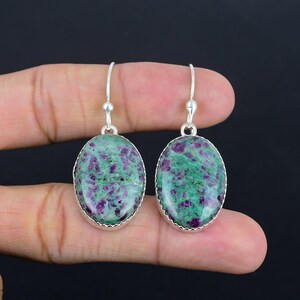 Peut inclure: Une paire de boucles d'oreilles en argent avec des pierres précieuses ovales de couleur verte et violette. Les boucles d'oreilles ont un design simple et sont parfaites pour un usage quotidien.