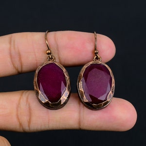 Peut inclure: Une paire de boucles d'oreilles en cuivre avec des pierres précieuses ovales, facettées, de couleur violet foncé.