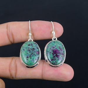 Peut inclure: Une paire de boucles d'oreilles en argent avec des pierres précieuses ovales de couleur verte et violette. Les boucles d'oreilles ont un design simple et sont parfaites pour un usage quotidien.