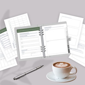 May include: A set of blank worksheets for business planning, including sections for industry research, goal setting, weaknesses and areas for improvement, and competitor analysis. The worksheets are laid out on a gray surface with a cup of coffee and a pen.