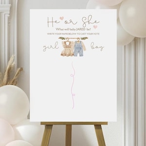 Op de afbeelding: Een wit bord met de tekst "He or She" en "What will baby JARED be?" met een roze hartje en een lijn van roze hartjes.  Het bord heeft ook een tekening van een babymeisjesoutfit en een babyjongensoutfit die aan een waslijn hangen.  Het bord zegt "Write your name below to cast your vote" en heeft de woorden "girl" en "boy" onder de outfits geschreven.