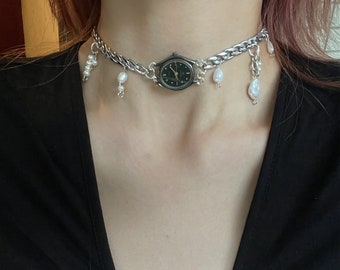 May include: A silver chain choker necklace with a small watch and pearl accents.
