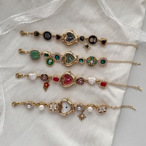 Può includere: Quattro braccialetti con ciondoli dorati con quadranti di orologi. Ogni braccialetto presenta un orologio a forma di cuore, insieme a vari ciondoli tra cui fiori, perle e forme geometriche. I quadranti degli orologi hanno sfondi di diversi colori.