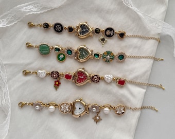 May include: Four gold-toned charm bracelets with watch faces. Each bracelet features a heart-shaped watch, along with various charms including flowers, pearls, and geometric shapes. The watch faces have different colored backgrounds.