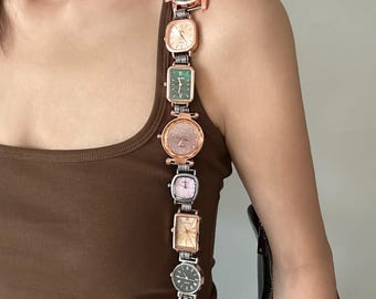 May include: A brown tank top with a silver chain strap featuring multiple small round and square analog watches with gold and green faces.