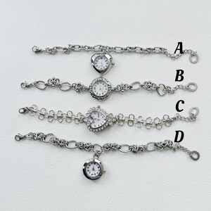 May include: Four silver wristwatches with different chain styles. The watches have round and heart-shaped faces with white backgrounds and black numbers. The watches are arranged vertically with the letter A, B, C, and D next to each watch.
