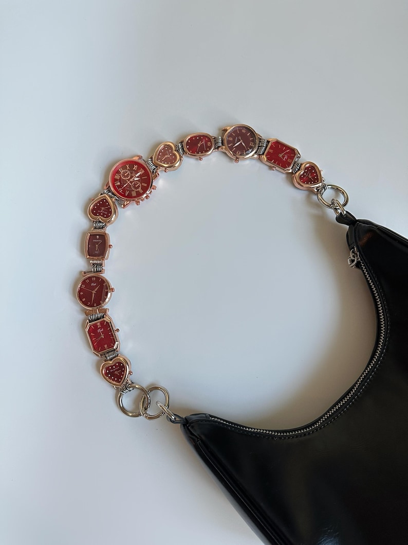 May include: A black leather handbag with a chain strap made of linked watches with red and gold accents.