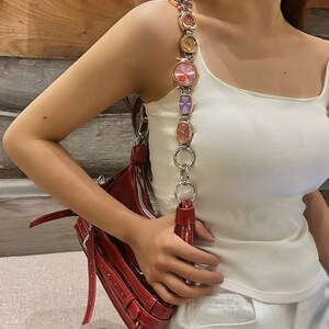 May include: A red leather shoulder bag with a chain strap featuring multiple colorful watch faces.
